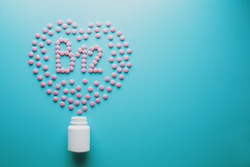 Pink tablets in the form of B12 in the heart on a blue background, spilled from a white can low...