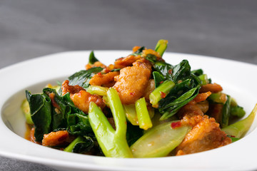 Fried Chinese kale with crispy skin chicken in oyster sauce and chilli in the white dish.