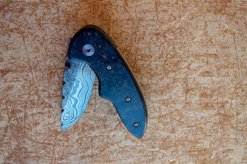 A very useful liner lock Damascus folding knife with box elder handle displayed on a pretty...