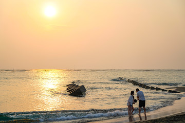 Golden Coast. The largest beach within Tainan, Taiwan. View from the beach with a yellow glowing sun setting in the horizon with a family enjoy fun here. 