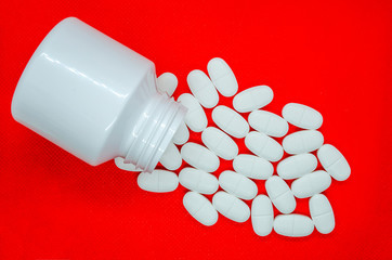 white tablets on a red background and a container for their storage - 267982486