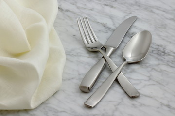 silverware and hemstitch napkin on antique carrara marble