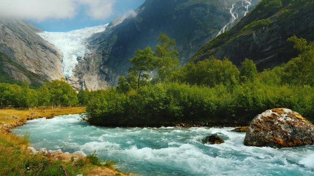 Clear water in a mountain stream against the background of a glacier in the mountains. Briksdal glacier and nature of Norway