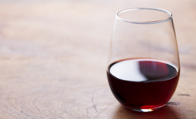 Glass of red wine on wooden table. Copy space. Close up.