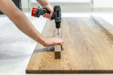 Man using screwdriver fasten plank on wooden table top