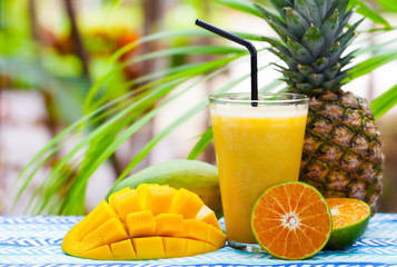 Fresh tropical fruit juice, smoothie in glass on summer outdoor background. Copy space.