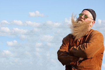 Mann mit langem Bart, der vom Wind verwirbelt wurde, steht am Ufer des Meeres
