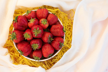 Fresh organic strawberry in the white bowl, on the wooden background. 
