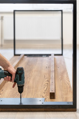 Man using screwdriver fasten metal element on wooden table top