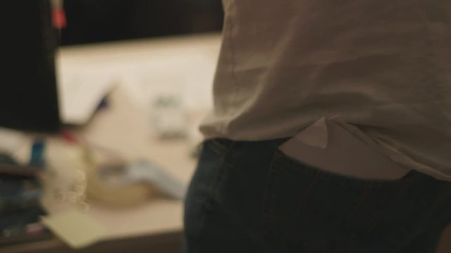 Handheld, close up shot of a piece of paper in the back of someone's pants pocket.