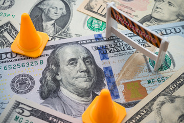 Traffic cone and dangerous under construction warning sign area on US dollar banknotes bill...