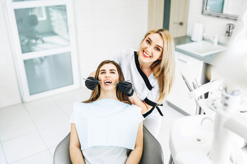 Pretty young female dentist making examination and treatment for young female patient in dental clinic.