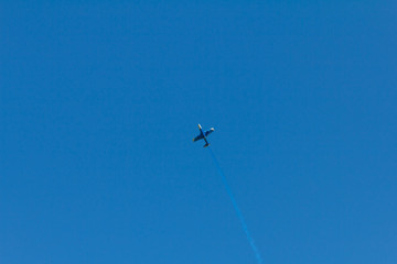 Condensation trace highlighted by the setting sun behind a plane in the blue sky. Condensation track the outdated inversion trail