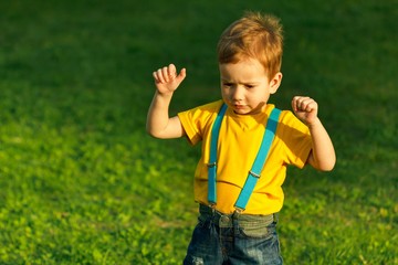 Boy on green grass lawn in summer park,  young.