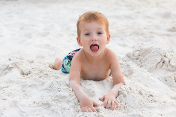 Little boy resting on a sandy beach