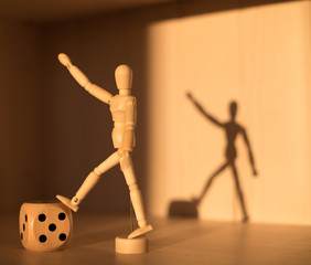 Wooden Dice cube and man casting a shadow. Conceptual still life. Abstraction of victory.