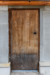 Old closed wooden door. A peeling, cracked, light brown door.