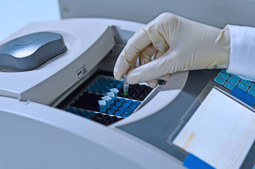 Scientist holding PCR tube put into PCR machine