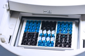 Scientist holding PCR tube put into PCR machine