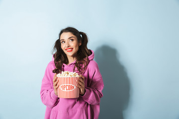 Portrait of pretty young woman with two ponytails smiling while holding popcorn bucket