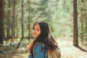 Naklejka premium brunette woman with backpack and denim jacket stands in the woods,selective focus