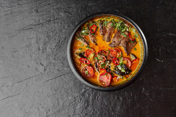 Kaeng Pled Ped Yang (Roasted Duck in Red Curry) , with rice. Thai cuisine. Restaurant, lunch, dinner. View from above. black stone background
