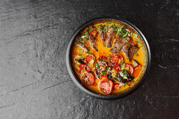 Kaeng Pled Ped Yang (Roasted Duck in Red Curry) , with rice. Thai cuisine. Restaurant, lunch, dinner. View from above. black stone background
