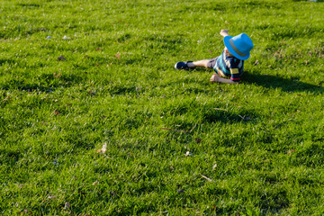 Obraz na płótnie Canvas Handsome little boy lying on grass. Little dreamer lies in meadow with hat. Child in nature outside city. Carefree vacation