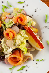 Salad with fresh salmon on a white plate close-up