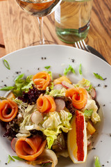 Fresh trout salad with greens and herbs on a white plate
