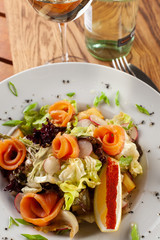 Fresh trout salad with greens and herbs on a white plate