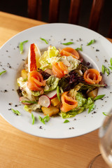 Fresh trout salad with greens and herbs on a white plate