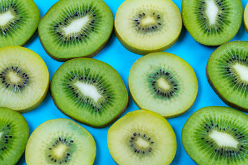 horizontal view of slices of golden yellow and green kiwi fruit on a bright high contrast turquoise background