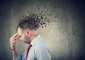 Side profile of a sad man losing parts of head as symbol of decreased mind function