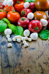 tasty colorful organic food ingredients for tomato mozzarella salad on a rustic wooden table