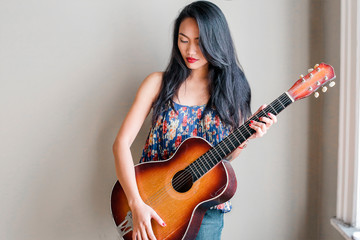 Fototapeta premium Pretty Asian woman playing on a guitar