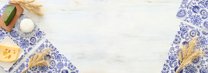 Top view photo of dairy products over white wooden background. Symbols of jewish holiday - Shavuot
