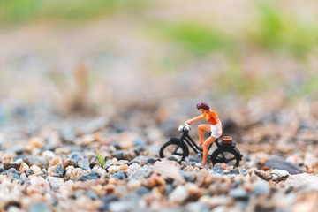 Miniature people : Travellers riding a bicycle  on The sand