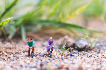 Miniature people : Travellers riding a bicycle  on The sand