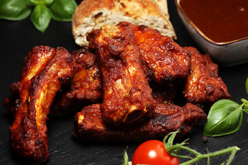 Spicy hot grilled spare ribs from a summer BBQ served with fresh tomatoes on an vintage cutting board