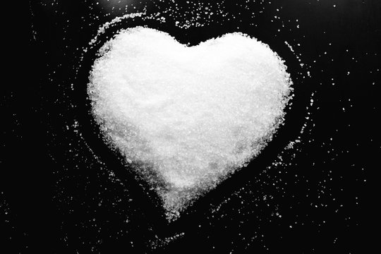 Abstract black and white photo in retro style with image of sweet heart made of white sugar on black background