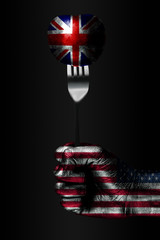 A hand with a drawn USA flag holds a fork, on which is a ball with a drawn Great Britain flag, a...