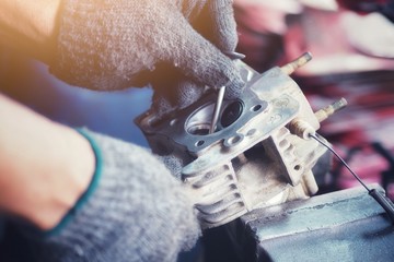 A motorcycle mechanic is repairing the cylinder head of a motorcycle.