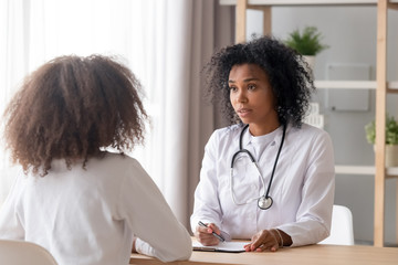 Friendly African American pediatrician doctor talking to teen girl