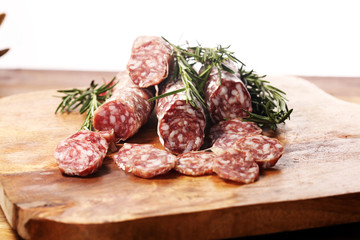 thinly sliced salami sausages on a wooden texture on the background.