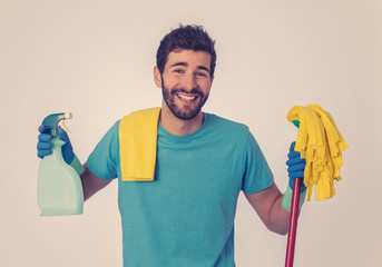 Young attractive man holding cleaning tools and products in bucket isolated in blue background