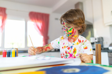 Blond child painting with colored face stained