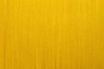 Yellow long spaghetti, top view. Thin pasta arranged in rows for the background. Yellow Italian pasta. Long spaghetti. Concept food background.