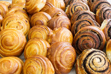 Close-up of baked sweet foods. Buns with poppy seeds, raisins, cream.