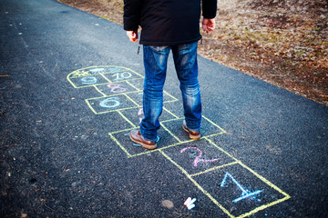 A young man playing hopscotch on asphalt. Good mood and spring in Russia. A bearded man recalls his...
